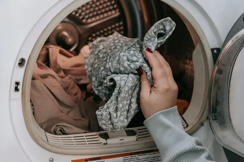 Hands loading laundry into a front-loading washing machine, an appliance whose supply hoses can burst in Cary, NC homes