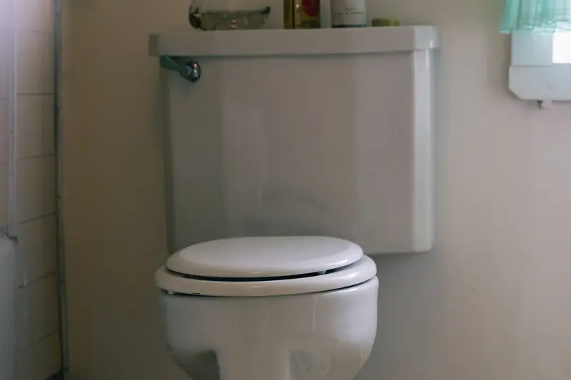 Toilet with a tank in a small bathroom, where an overflow can soak the floor and the ceiling below in Cary, NC homes