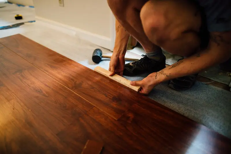 Installer fitting hardwood flooring boards, the kind of floor replacement that follows serious water damage in Cary, NC