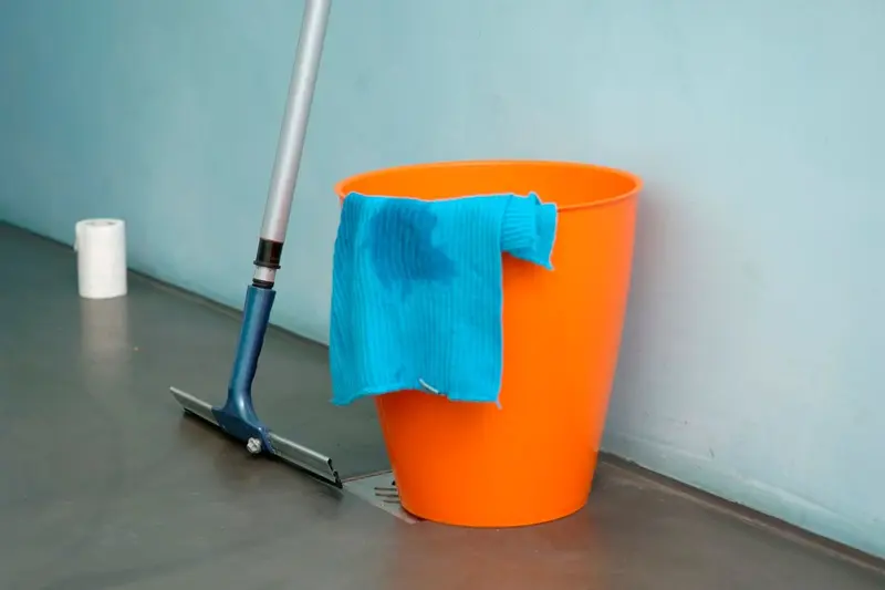 Bucket, mop and cloth on a wet floor, the first cleanup steps after water damage in a Cary, NC home